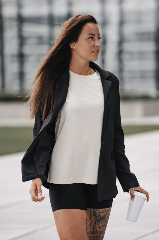 Cremeweißes T-Shirt mit großem Rückendruck in Flieder. Der Textaufdruck lautet: „FIND ME WHERE THE LOVE, HARMONY AND THE SUN ARE“, ergänzt durch ein kleines grafisches Sonnensymbol am unteren Rand.