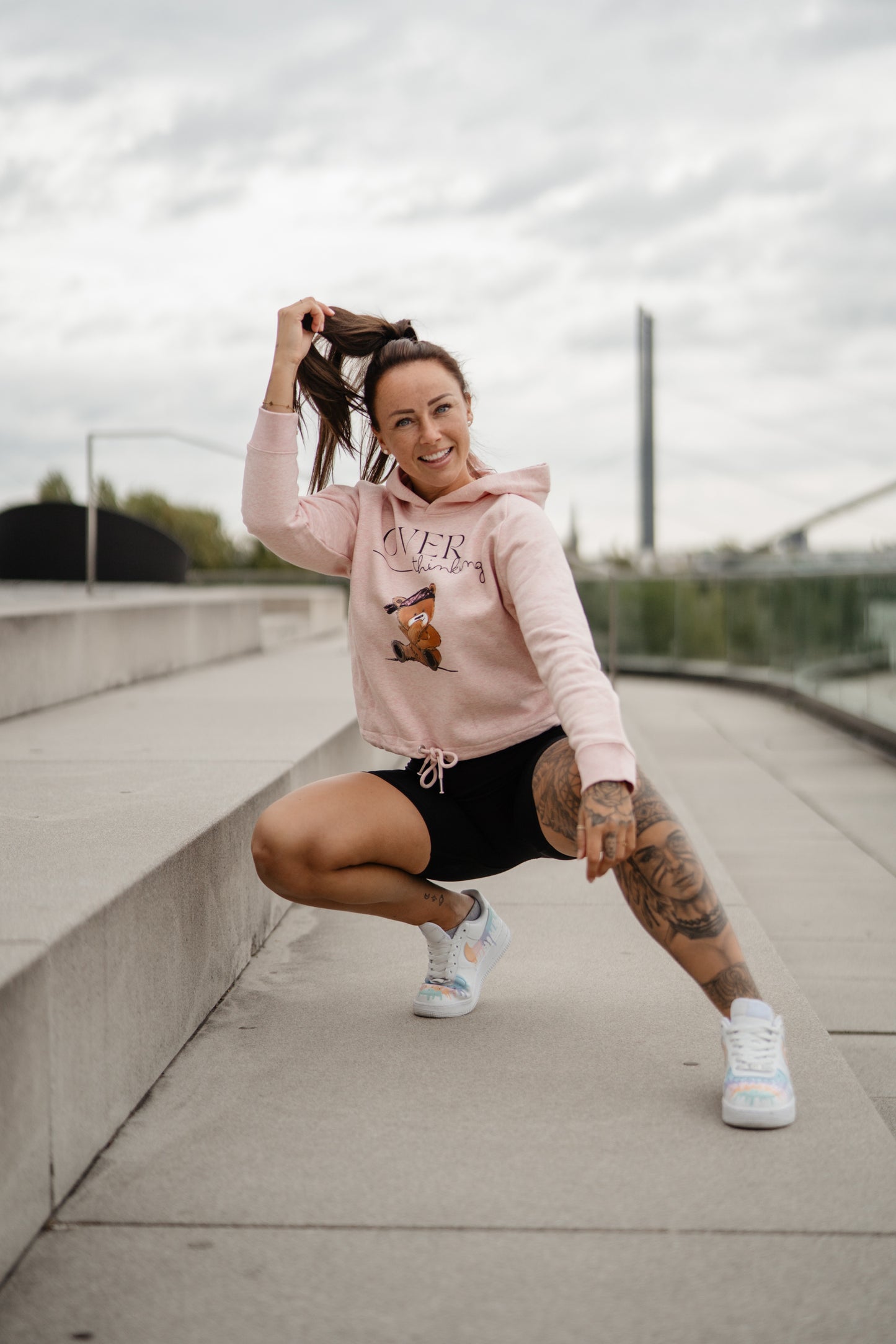 Hellrosa Damen-Hoodie mit Frontprint „OVERthinking“ und einem illustrierten Bärenmotiv. Der Kapuzenpullover hat eine Kordel am Bund zum Binden, lange Ärmel und eine weiche, leicht melierte Optik.