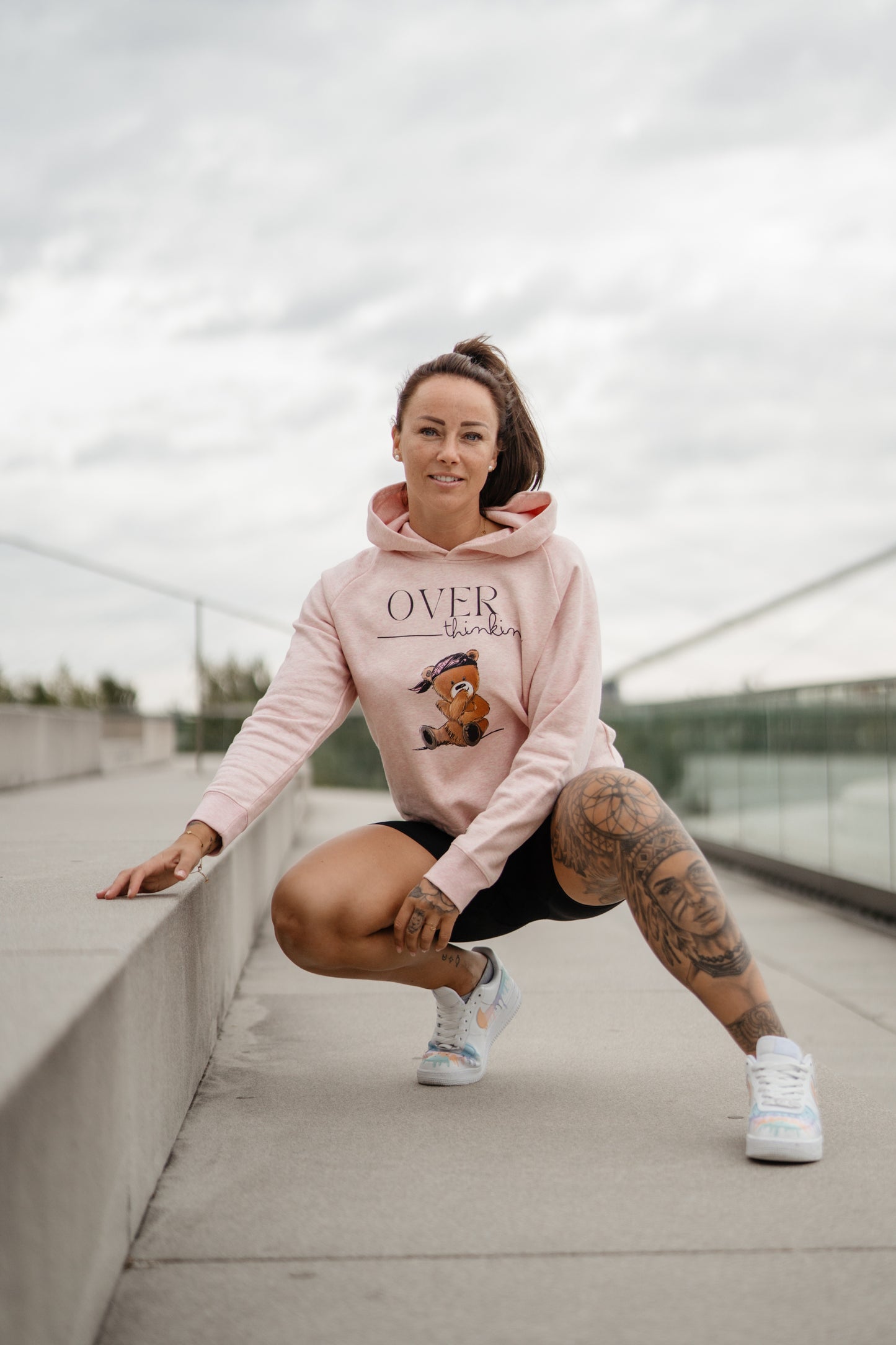 Hellrosa Damen-Hoodie mit Frontprint „OVERthinking“ und einem illustrierten Bärenmotiv. Der Kapuzenpullover hat eine Kordel am Bund zum Binden, lange Ärmel und eine weiche, leicht melierte Optik.