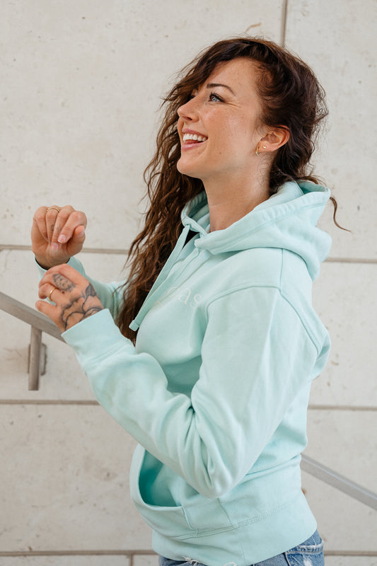 Hellblauer Kapuzenpullover mit weißem Frontprint in feiner Serifenschrift. Der Aufdruck zeigt die Worte „Pourquoi pas“ sowie darunter „WHY NOT“. Der Hoodie verfügt über eine doppellagige Kapuze mit Kordelzug, eine Kängurutasche und breite Rippbündchen an Ärmeln und Saum.