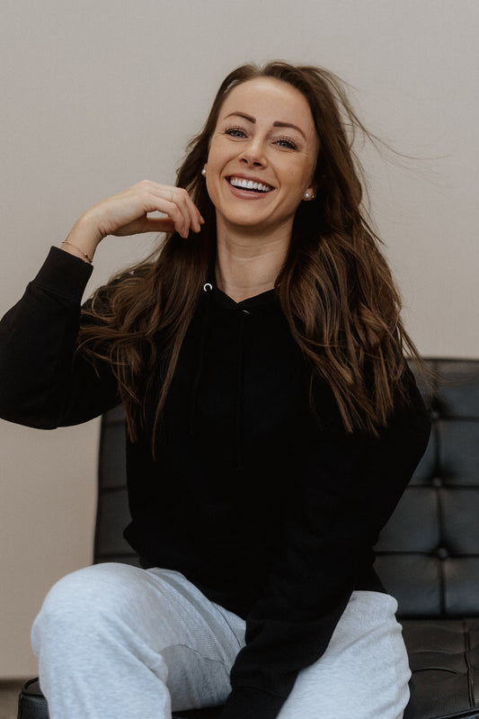 Schwarzer Hoodie mit weißem Rückendruck in zwei Schriftstilen: „PERFECTLY“ in Blockbuchstaben und „imperfect“ in geschwungener Schreibschrift. Der Print sitzt mittig auf dem oberen Rücken.