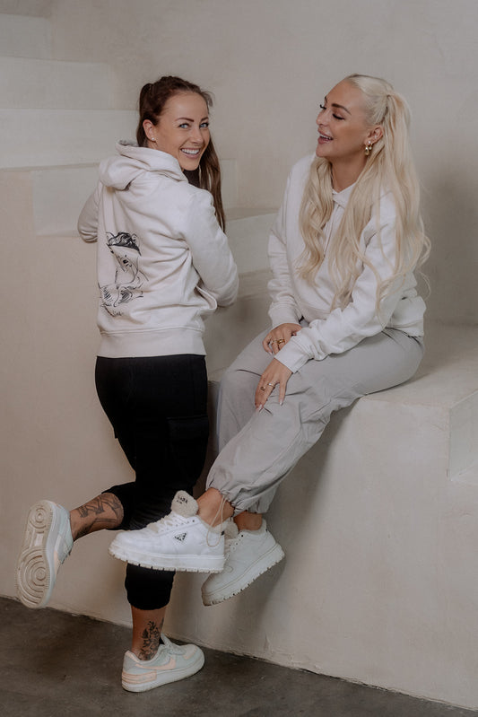 Rückansicht eines weißen Hoodies mit großem schwarzem Print eines nachdenklich wirkenden Bären, der ein Stirnband trägt. Unter dem Motiv steht in geschwungener Schrift der Schriftzug „Overthinking…“.